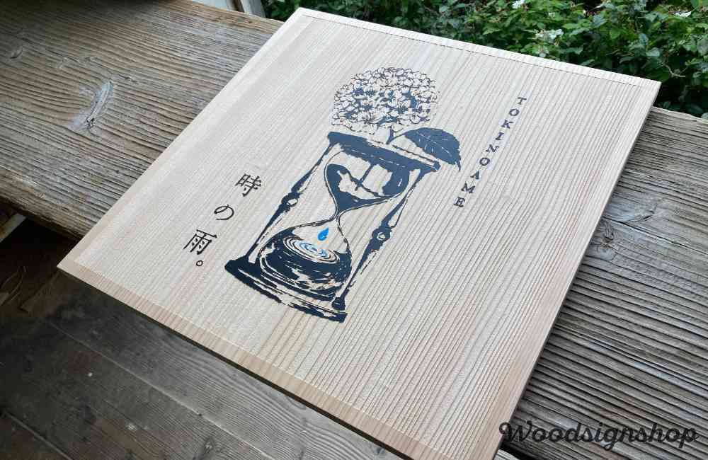 無塗装の縦木目にサンドブラストされた木製看板の中央に砂時計とアジサイのロゴ、ブルーの滴が美しい木の看板