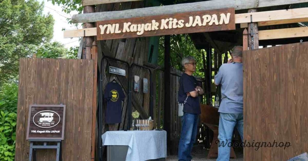木製の看板が設置されたYNL Kayak Kits JAPANの店舗入り口。看板には「YNL Kayak Kits JAPAN」の文字とカヤックのロゴが描かれ、木造の外観と調和している。
