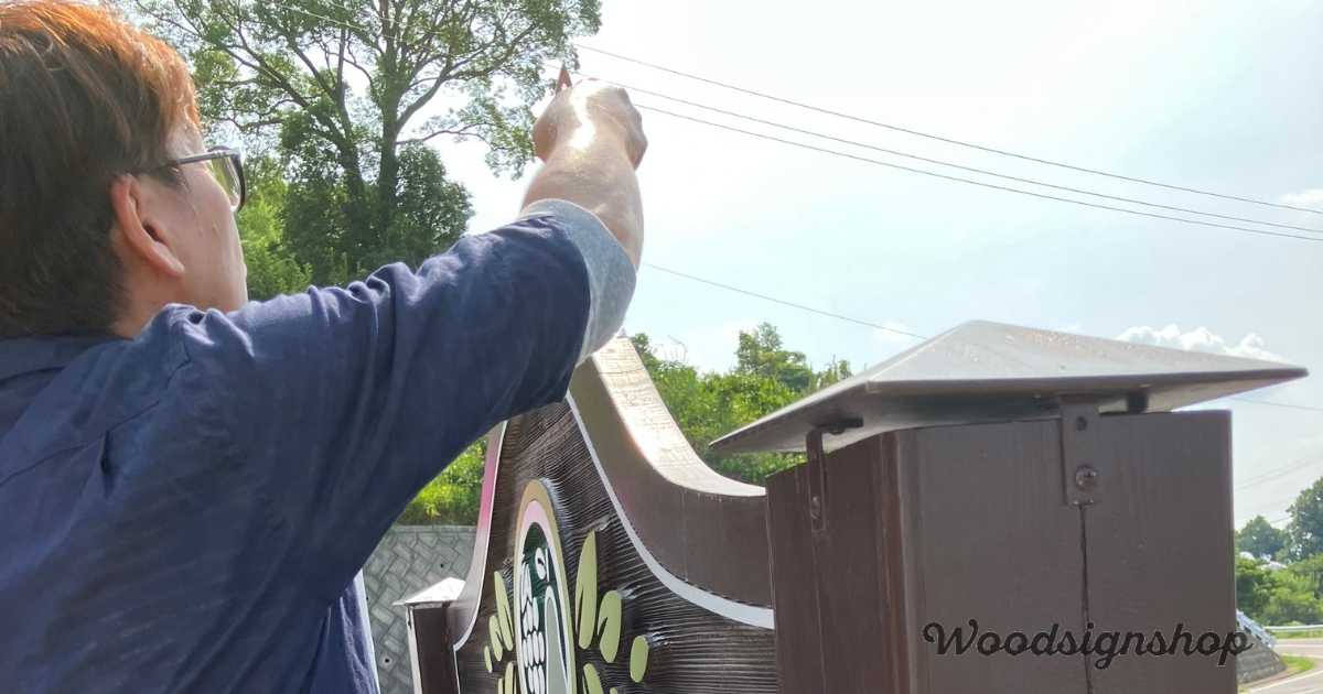 木製看板の上面を塗装している作業写真