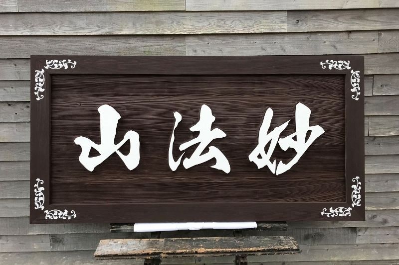 佐賀県佐賀市 賀昌院様の山号額「妙法山」の正面写真。唐草模様の装飾と迫力ある筆文字が見える木製額。