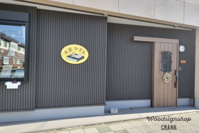 静岡市葵区「本屋ひるね」様の外壁に設置された楕円形の木製店舗看板と奥に二世帯木製表札
