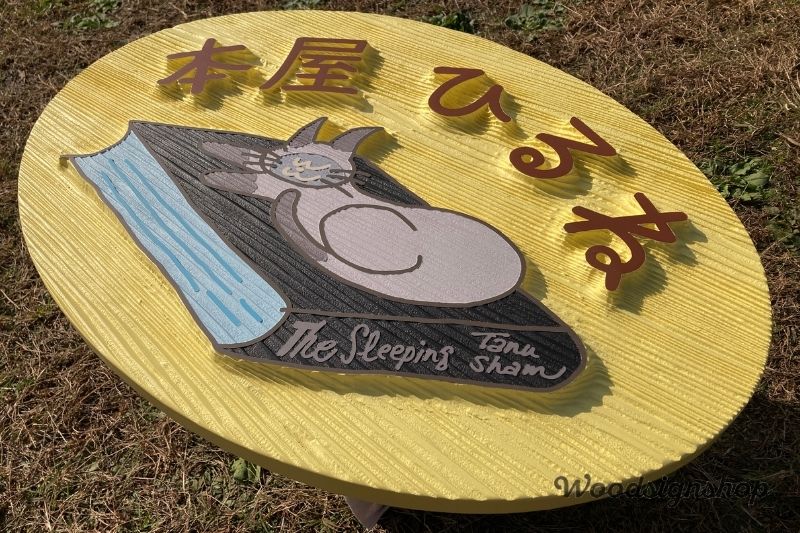 太陽光で強調される木製看板の凹凸質感。サンドブラスト加工で仕上げた「本屋ひるね」の立体サイン。