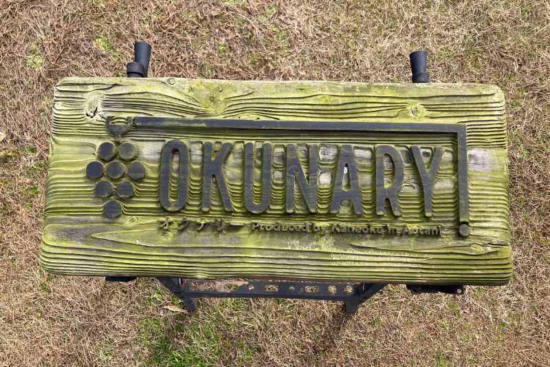 湿気の多い場所に設置され、表面に苔が生えた木製看板。