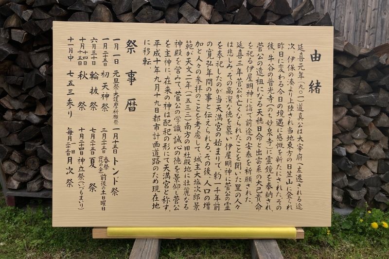 薪の前に置かれた、防腐塗料仕上げで新しく仕上がった木製由緒書き看板