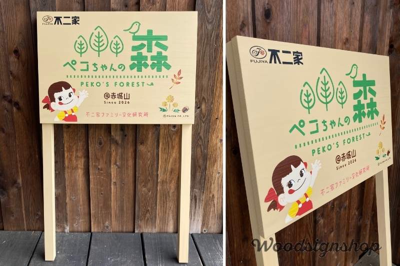 工房の木壁の前に置かれた「ペコちゃんの森」木製看板の2分割写真。左側はすっきりとした脚付きの正面全体、右側は斜めからのアングルで、木の温かみのある質感や丁寧な仕上げ、しっかりとした厚みが確認できます。